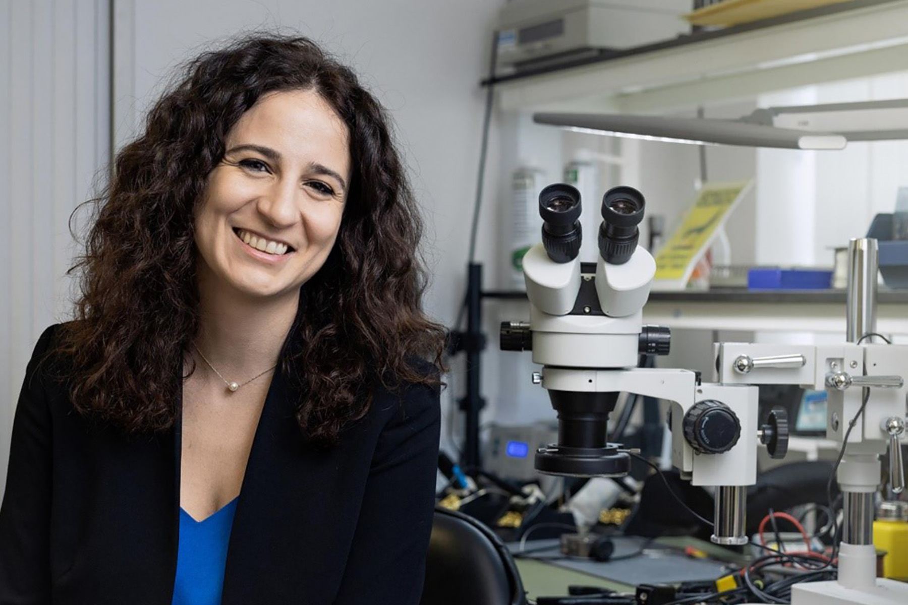 Dr Giorgia Longobardi winner of a Cambridge Enterprise Postdoc Business Plan Competition seated in a lab next to a microscope