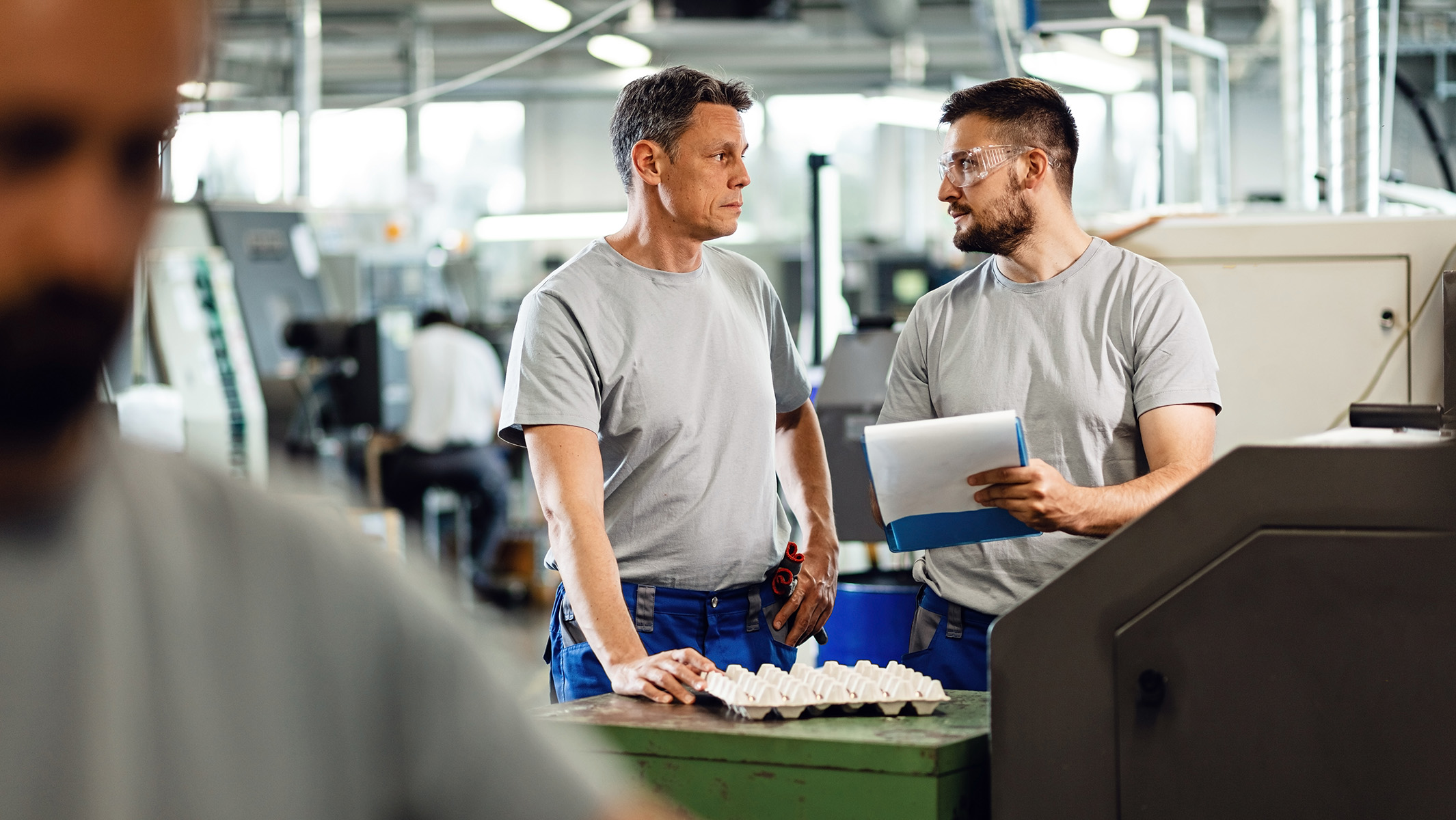 male coworkers communicating while going though paperwork factory